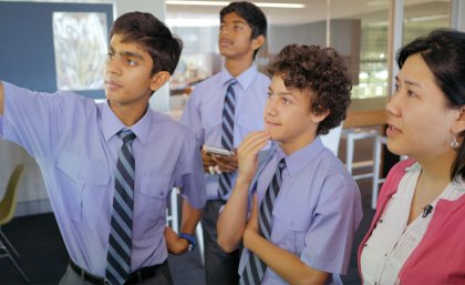 Brisbane Grammar School students with Head of Physics Noël Chan discuss the outcomes of their experiment on acceleration due to gravity.